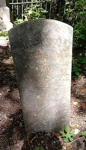 Dirty headstone covered in moss and lichen before professional cleaning